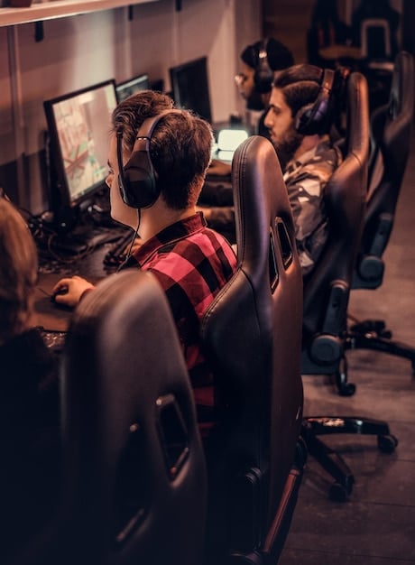 A behind-the-scenes shot of a US esports team intensely practicing in their gaming house, surrounded by monitors displaying the game and stats, highlighting their focused environment and dedication to adapting to Patch 14.25.