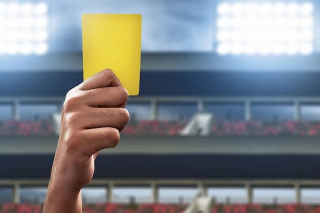 A close-up, high-resolution image of a referee's hand holding up a yellow card during an esports match, with bright stadium lights and blurry gaming action in the background, signifying strict rule enforcement and consequence.